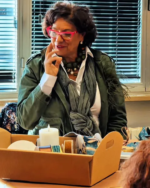 Maria Teresa Pelosi sorride al tavolo della demo di packaging, accanto a un cesto con candela e nastri