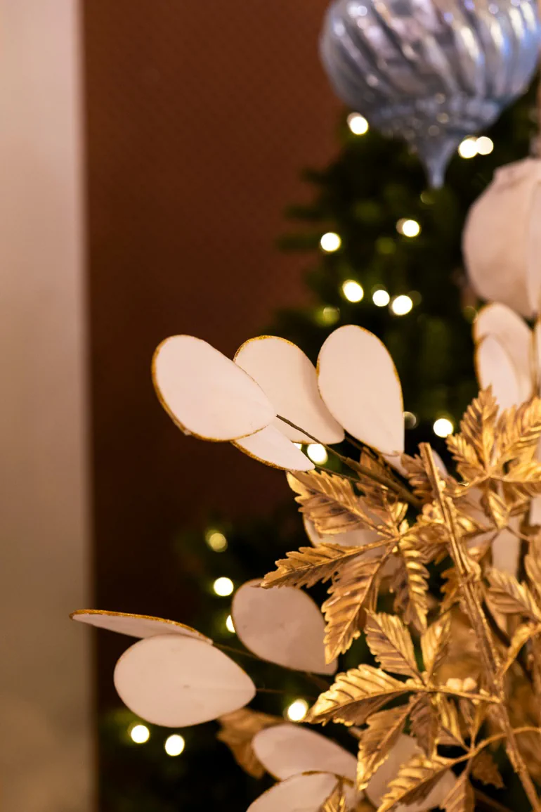 Foglie dorate e rami di lunaria davanti all'albero illuminato